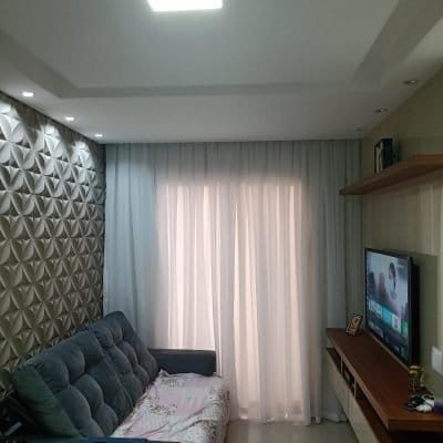 Cortina de tecido sob medida da JF Persianas instalada em sala de estar, com forro leve e blackout para controle de luz.